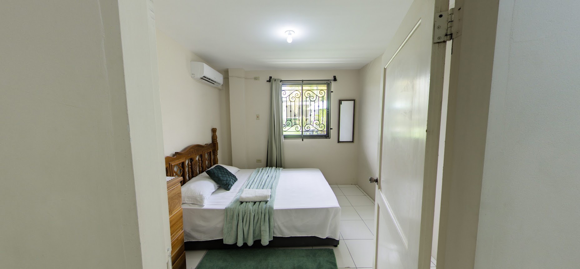 Garden suite bedroom with wooden headboard and green accents
