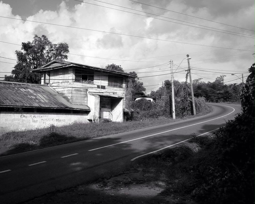 A curving road through a Moruga village, past a weathered wooden shopfront