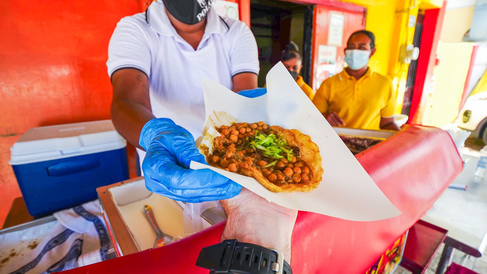 Freshly made doubles with curried channa and shado beni handed over at a roadside stall in South Trinidad