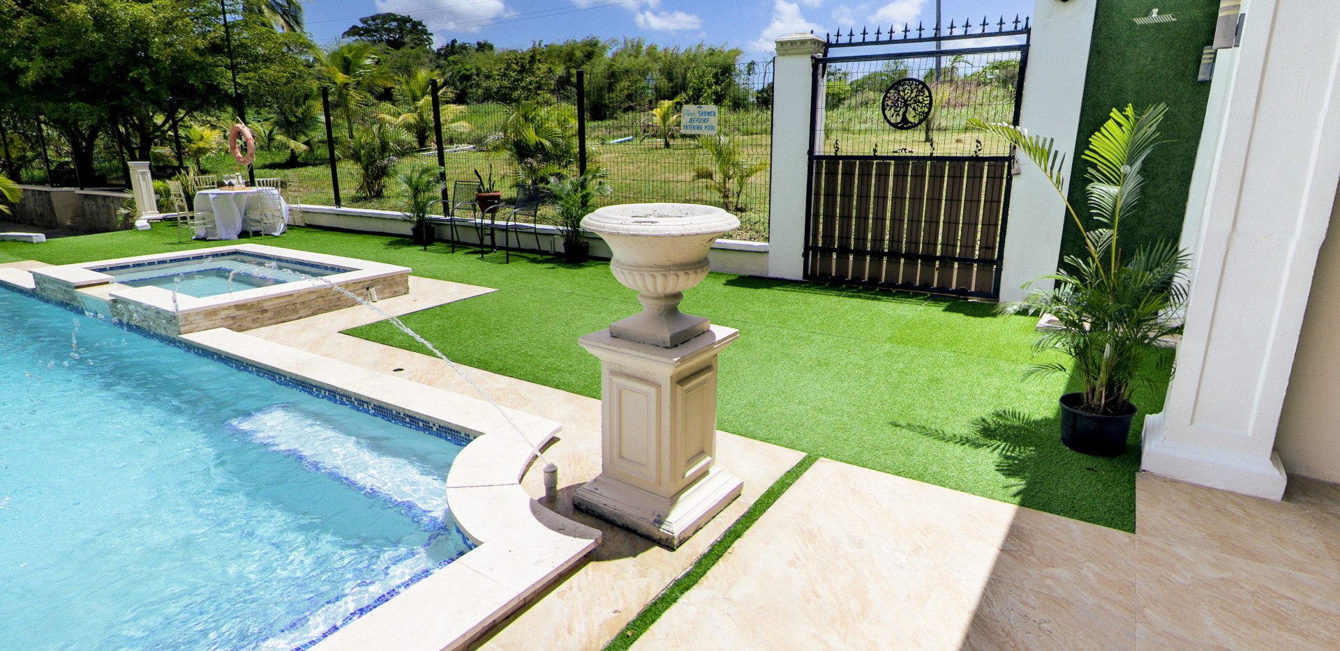 Fountain urn beside pool with jacuzzi and iron gate