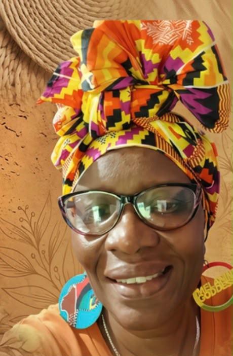 Cultural host in a vibrant African headwrap welcoming guests to the Orisha heritage visit near Moruga