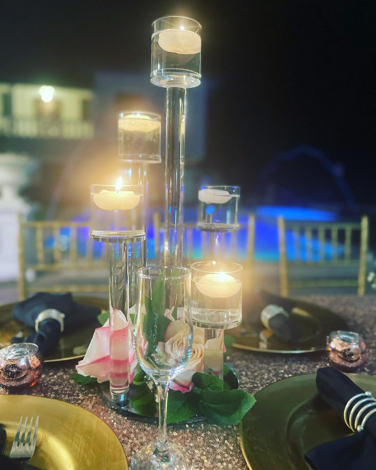 Floating candle centerpiece on a poolside dinner table at night