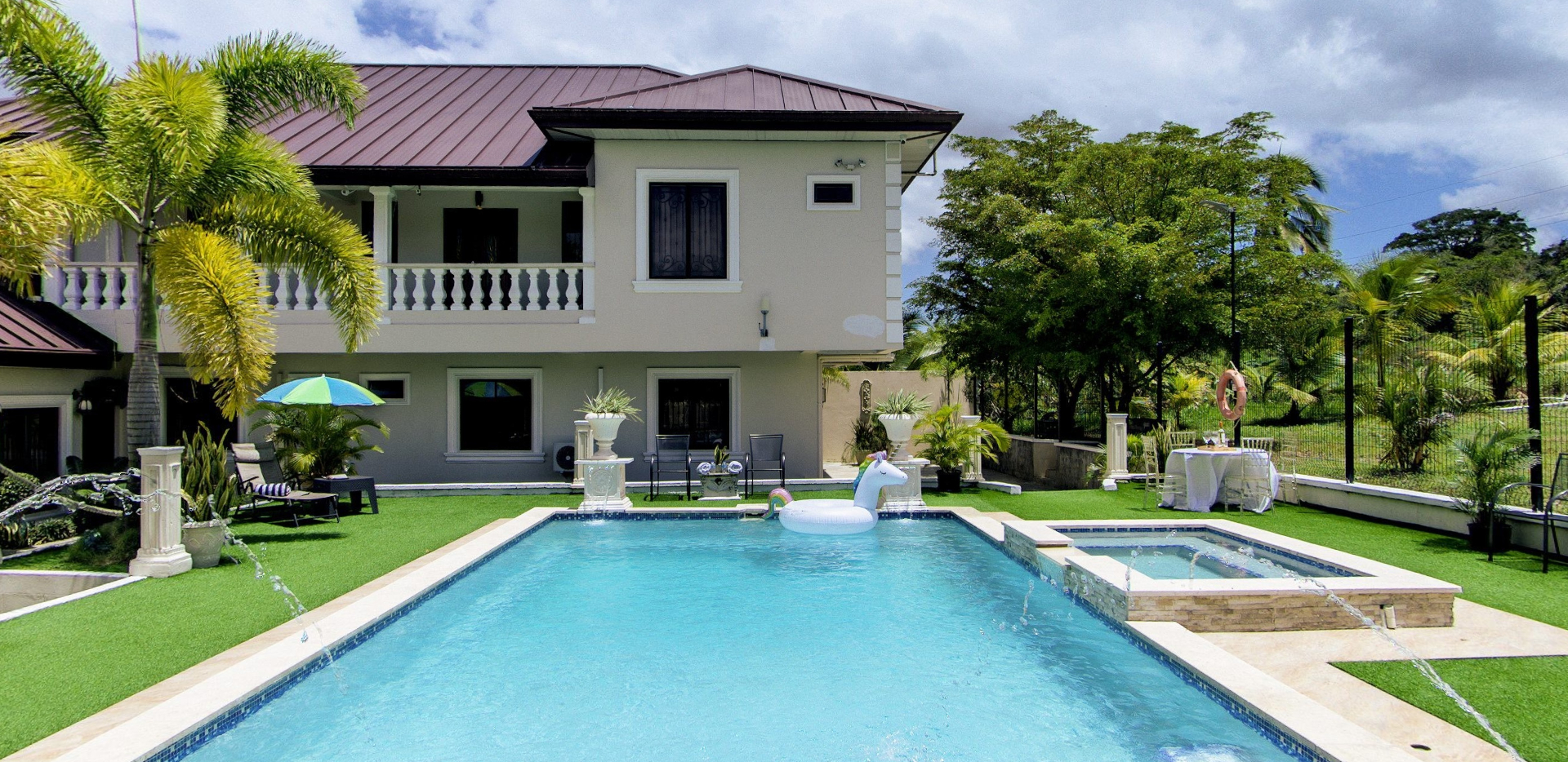 Villa exterior with pool, jacuzzi and unicorn floatie under blue skies
