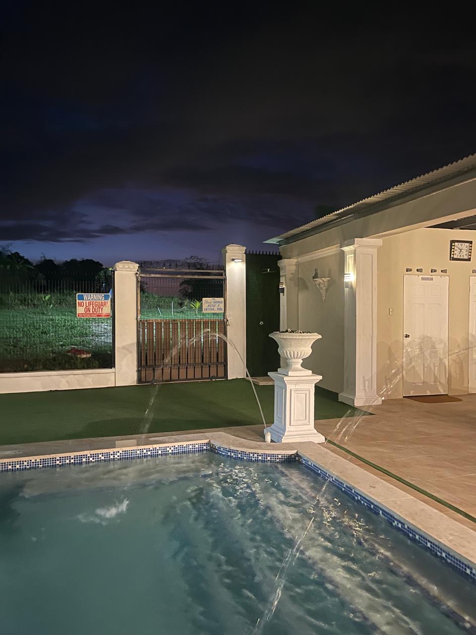 Pool and fountains lit at night beside the villa